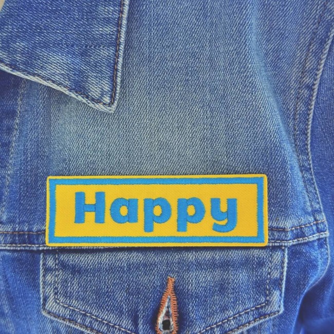 Détail du patch brodé Happy sur denim Gros plan sur le patch mot personnalisé Happy brodé sur veste en jean