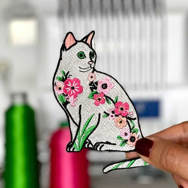 Chat brodé thermocollant fleuri, tenu en main dans mon atelier de broderie