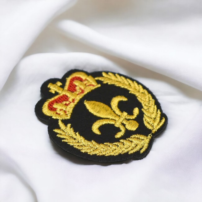 Détail du patch thermocollant brodé fleur de lys sur tissu blanc