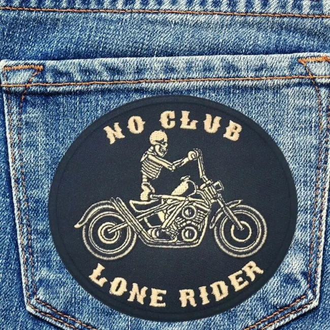 Patch biker, patch No club Lone rider, écusson brodé noir et beige sur un jean Patch biker No Club Lone Rider beige posé sur une poche en jean