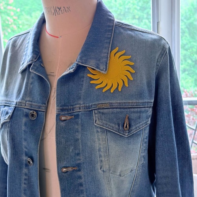 Patch soleil jaune posé sur une veste en jean
