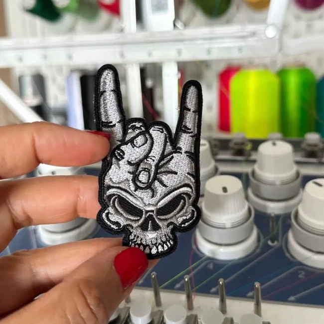 Détail du motif rock brodé avec cornes du diable Gros plan sur la broderie du patch main rock et crâne