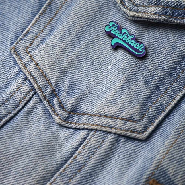 Pin’s Flashback rétro porté sur veste en jean avec un look vintage Broche Flashback en émail coloré posée sur une veste en jean