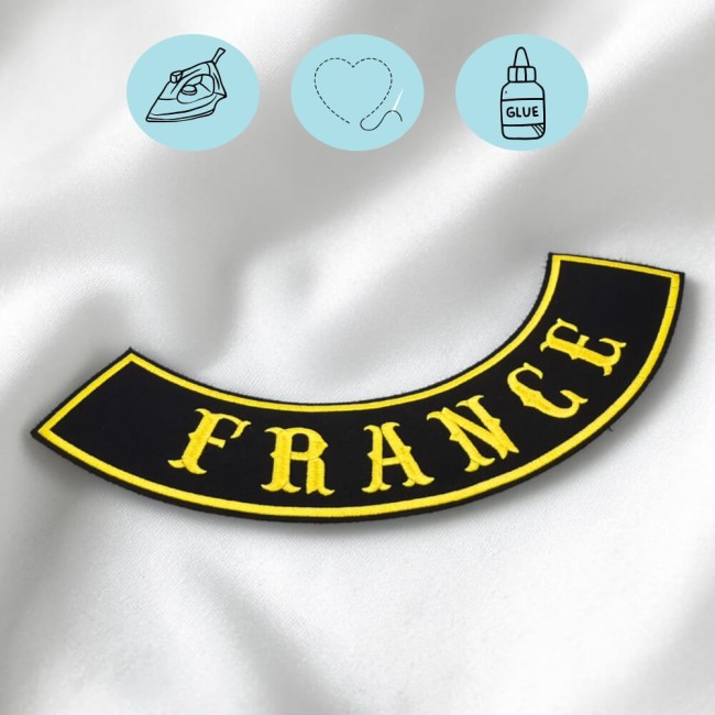 Détail de broderie sur patch biker personnalisé avec fil jaune, tissu noir et bordure brodée