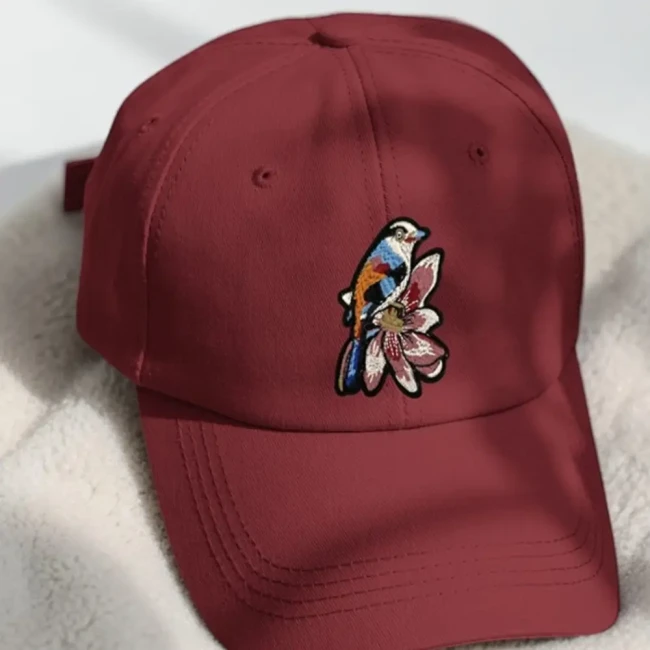 Patch oiseau sur fleur posé sur une casquette Patch brodé oiseau et fleur appliqué sur une casquette bordeaux