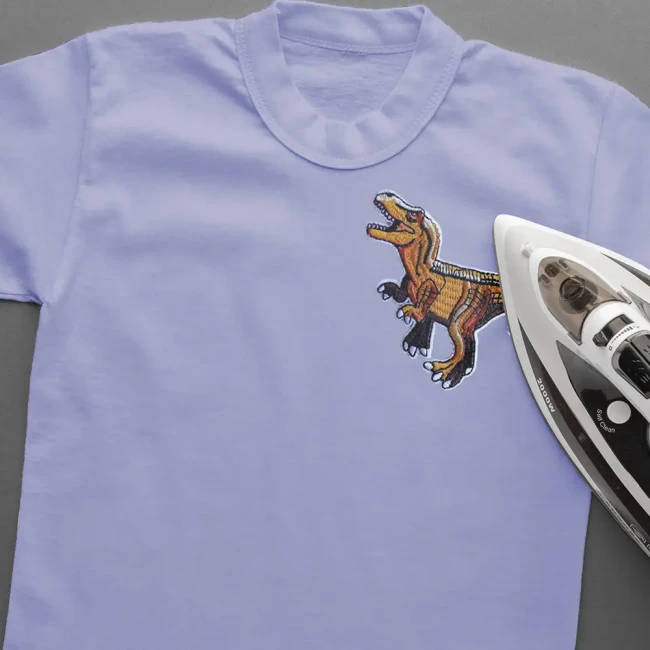 Pose au fer d’un patch dinosaure brodé sur un T-shirt