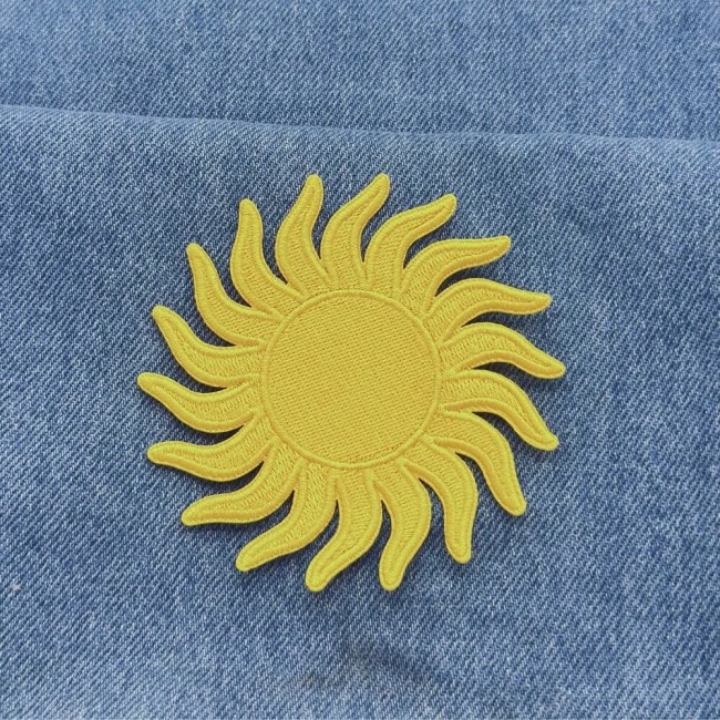 Patch soleil jaune thermocollant posé sur un jean