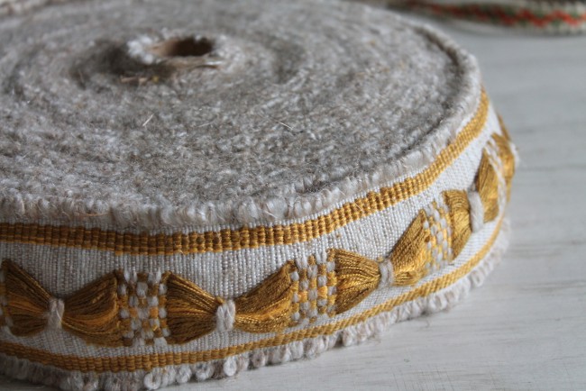 Détail d’un galon de passementerie ancienne fabriqué en France, dans un élégant coloris noisette. Sa texture épaisse et ses motifs décoratifs en relief en font un bel élément pour la confection d’embrasses de rideaux, la décoration de meubles, la restaura