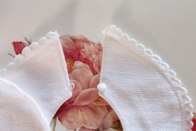 Gros plan sur le boutonnage du bavoir ancien pour poupée ou nourrisson 