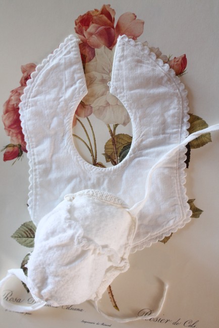 Gros plan sur le bavoir et le bonnet anciens de poupées blancs
