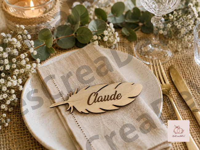 Marque-place mariage en bois en forme de plume gravé au prénom de l'invité présenté sur une serviette en lin