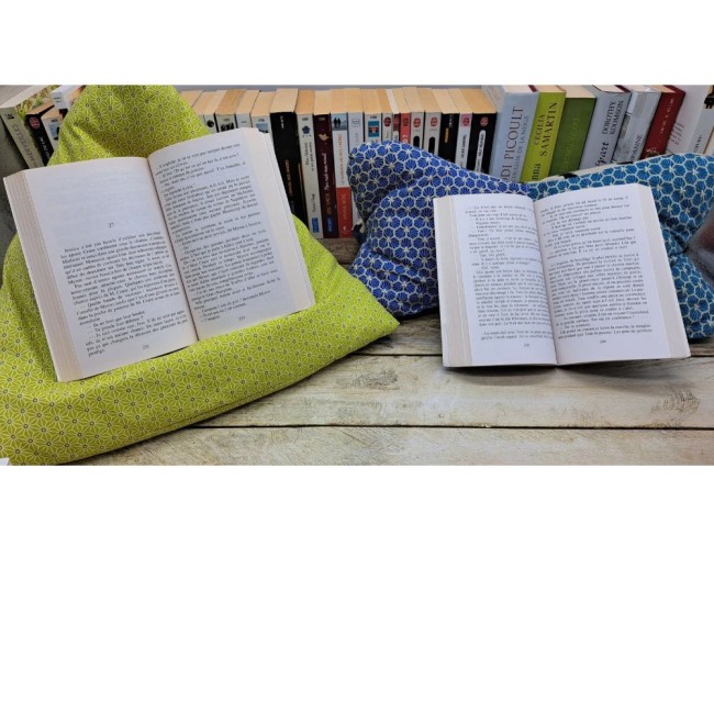Deux livres ouverts, l'un posé sur un support textile vert à motifs géométriques et l'autre sur un support bleu à motifs.