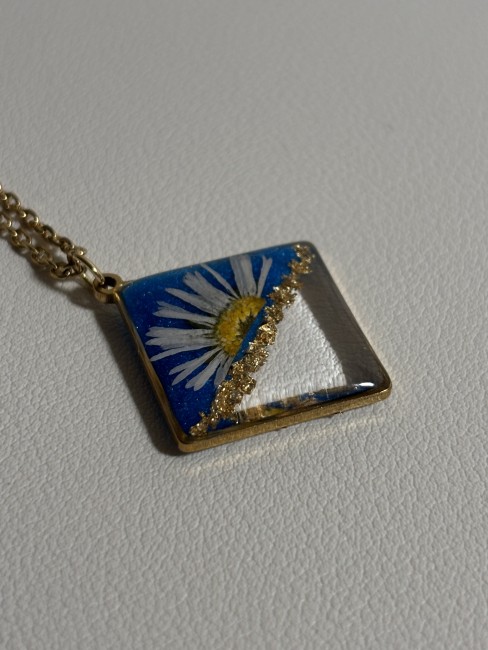 Collier demi-pâquerette bleue porté par un