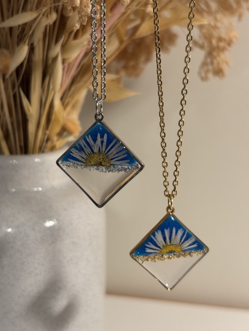 Collier avec demi-pâquerette dans un pendentif en résine bleue et transparente