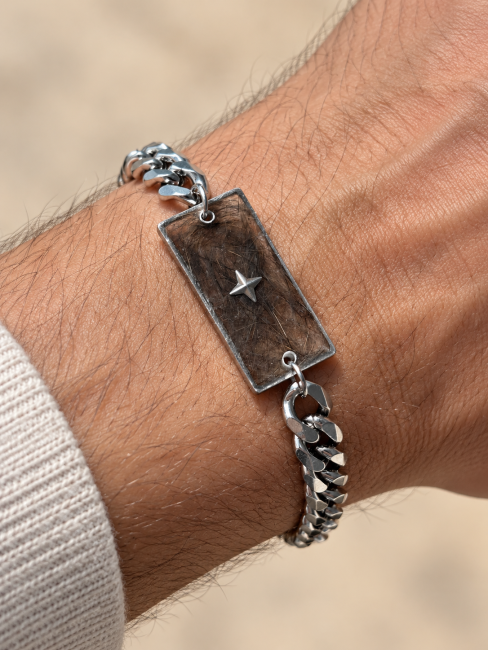 bracelet souvenir avec poils d’animaux Bracelet souvenir en acier inoxydable avec inclusion de poils dans la résine et petite étoile argentée, porté sur un poignet d’homme.