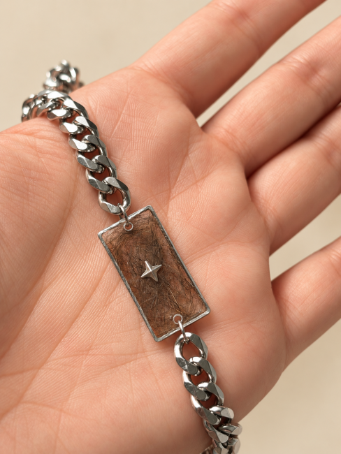 Bracelet souvenir personnalisé avec poils d’animaux Bracelet souvenir en acier inoxydable posé dans une main, avec poils inclus dans une plaque en résine et étoile argentée