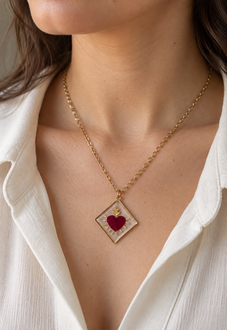 Collier doré cœur ex-voto en pétale de rose et résine transparente, porté par une femme.