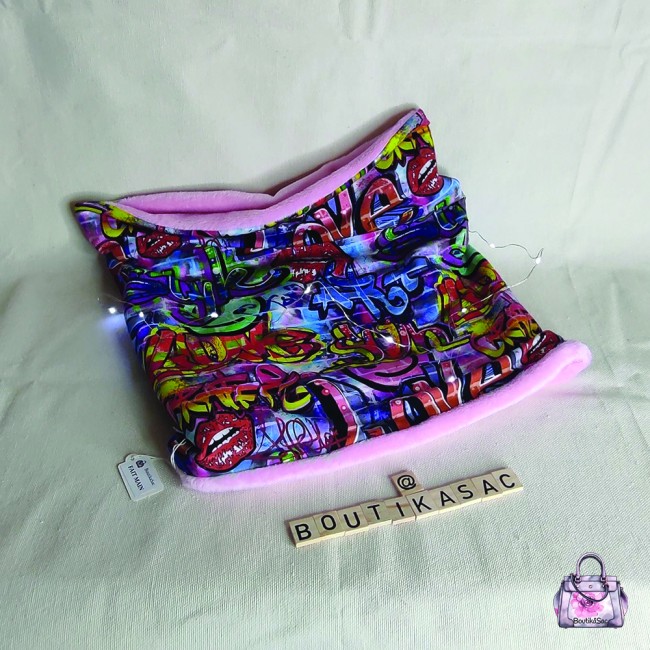 Image du snood posé à plat, montrant les deux faces : graffiti et polaire rose.