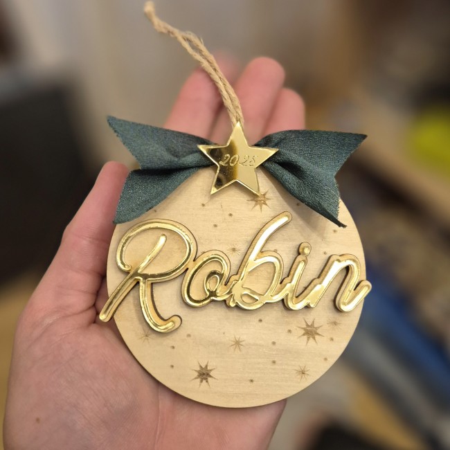 alt=Boule de Noël « Mon Premier Noël » en bois gravé avec prénom et année, l'Atelier de Célestine